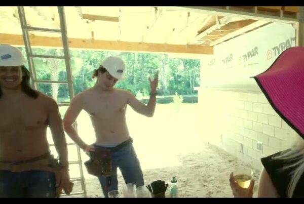 two fit shirtless bartenders dressed in construction gear work a realtor open house at a new custom home build project