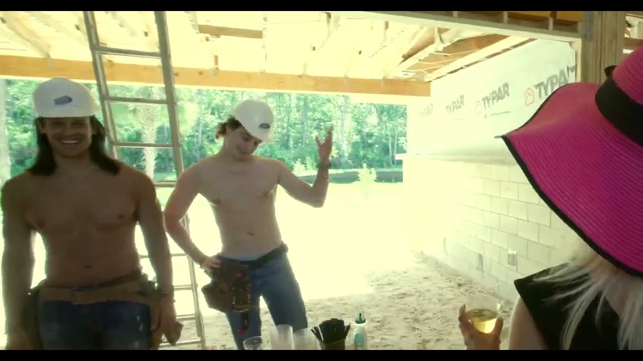 two fit shirtless bartenders dressed in construction gear work a realtor open house at a new custom home build project