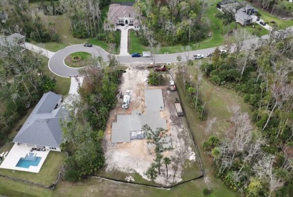 Image taken from drone looking down on new residential home build site with concrete slab foundation recently poured into frame