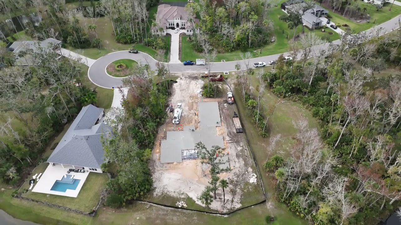 Image taken from drone looking down on new residential home build site with concrete slab foundation recently poured into frame