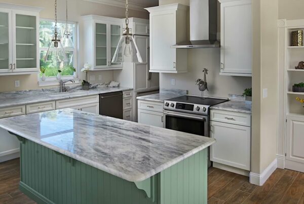 kitchen with marble countertop island, white cabinets with glass panel doors and light green accent color on several cabinet bases