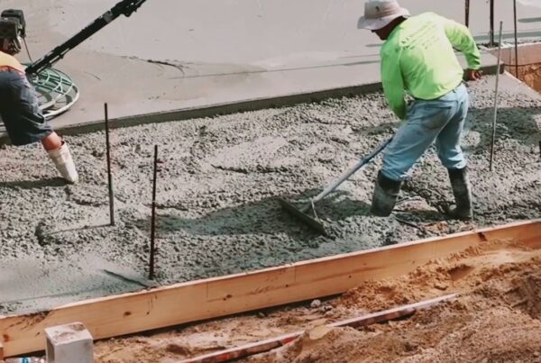 construction worker stands in wet cement and evens surface with hand held equipment