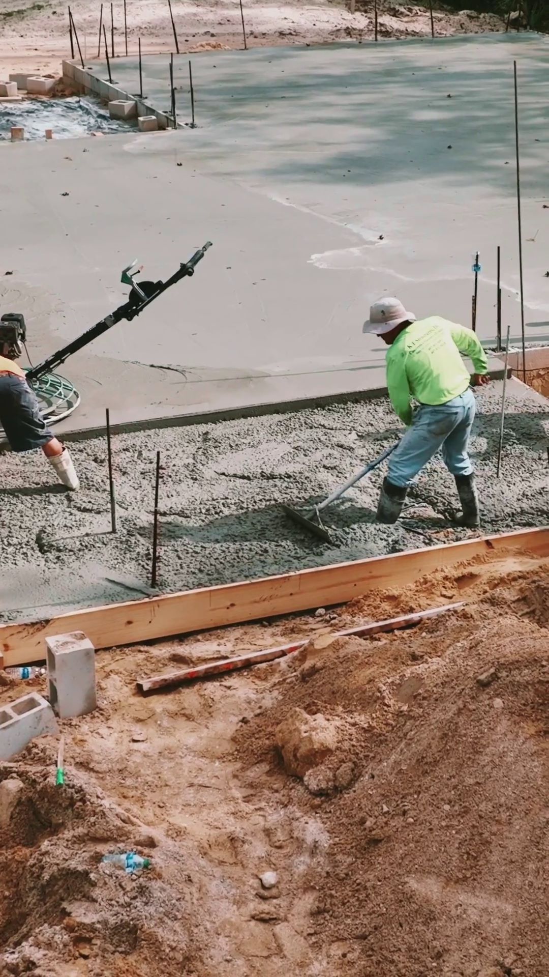 construction worker stands in wet cement and evens surface with hand held equipment