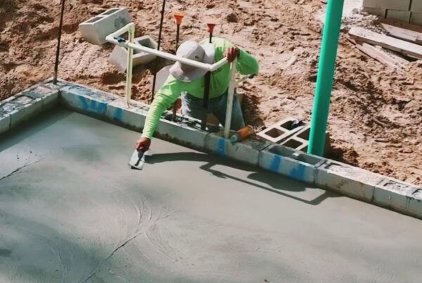 construction worker smooths wet concrete by hand