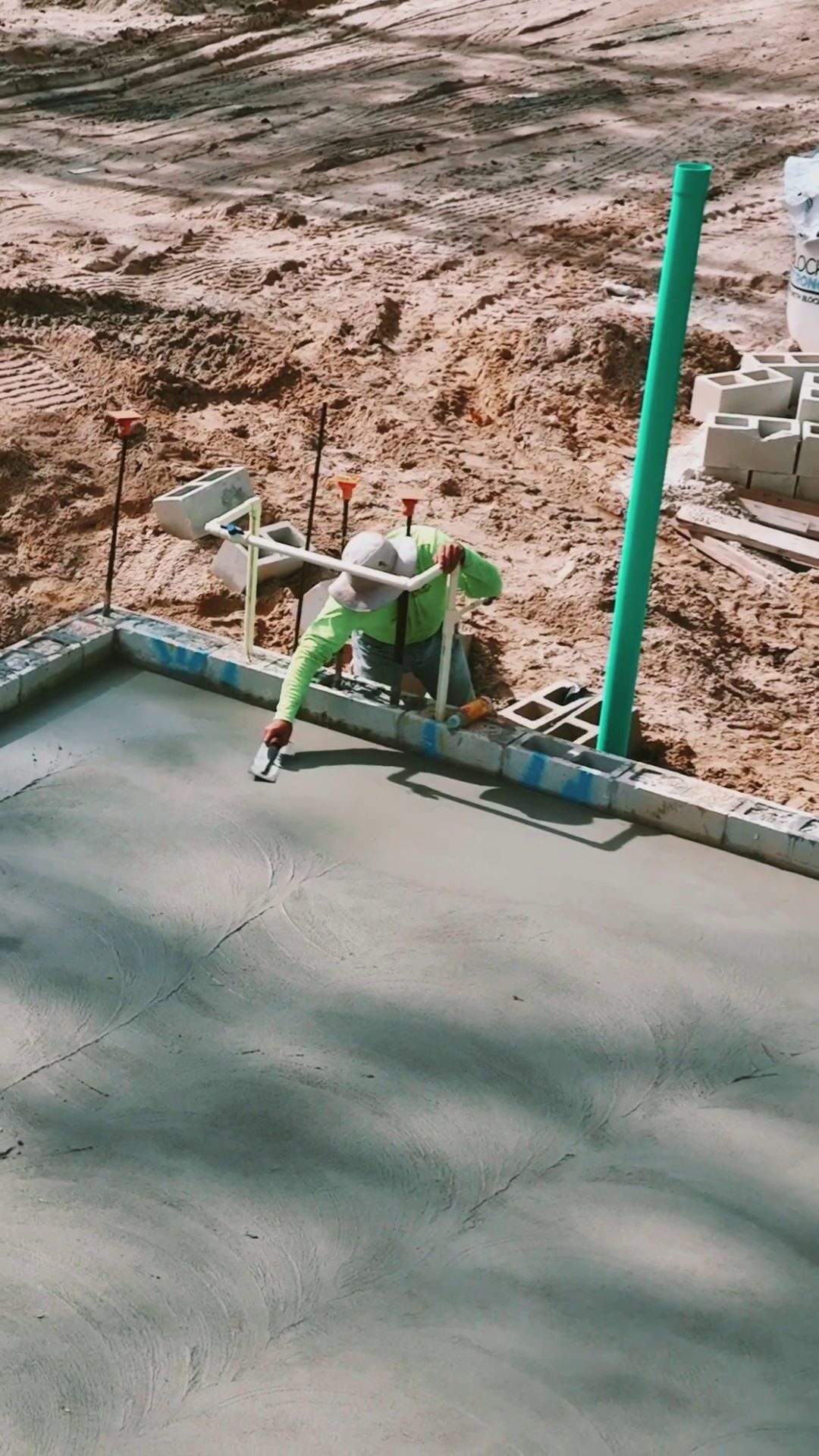 construction worker smooths wet concrete by hand