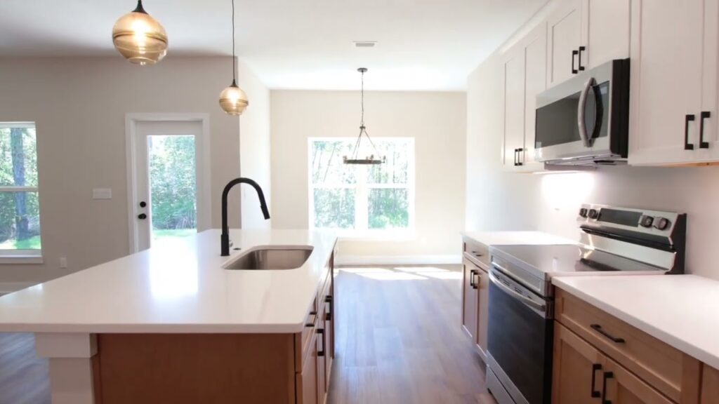 new kitchen shown with island and kitchen sink with faucet on left, and stove with cabinets and microwave oven on right