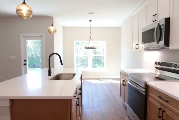 new kitchen shown with island and kitchen sink with faucet on left, and stove with cabinets and microwave oven on right